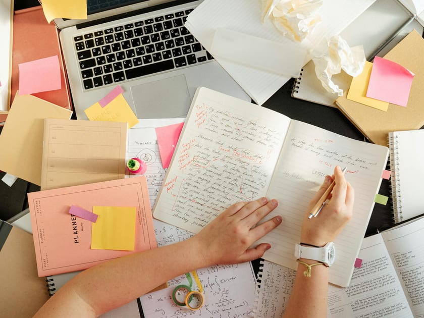 Overhead view of notes, laptop, and study materials on a working desk