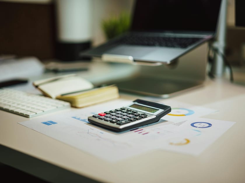 Calculator, laptop, and documents arranged on a professional desk