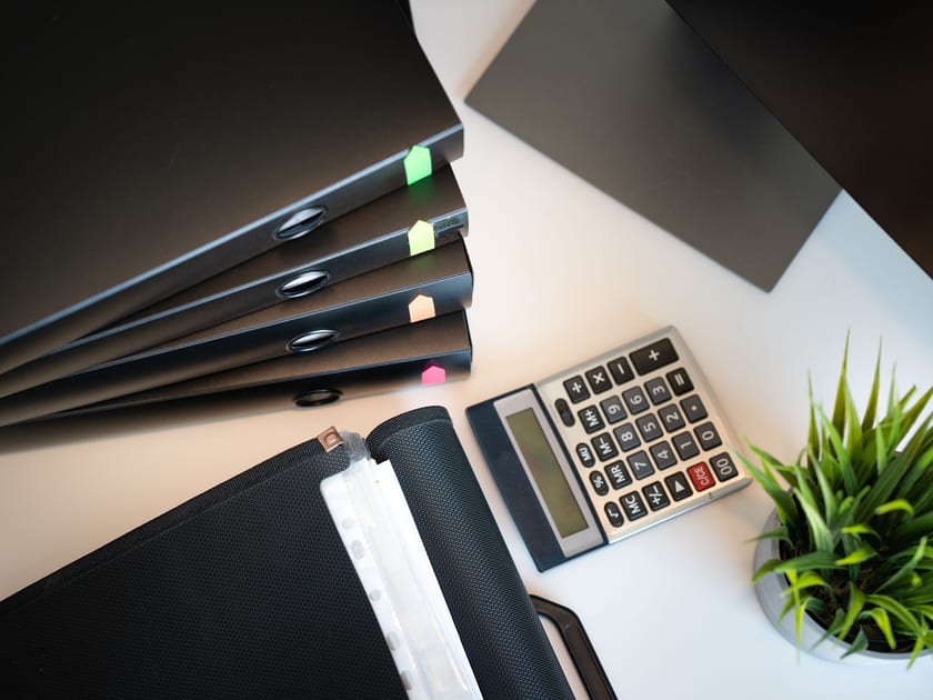 Files, calculator, and plant arranged on a tidy office desk