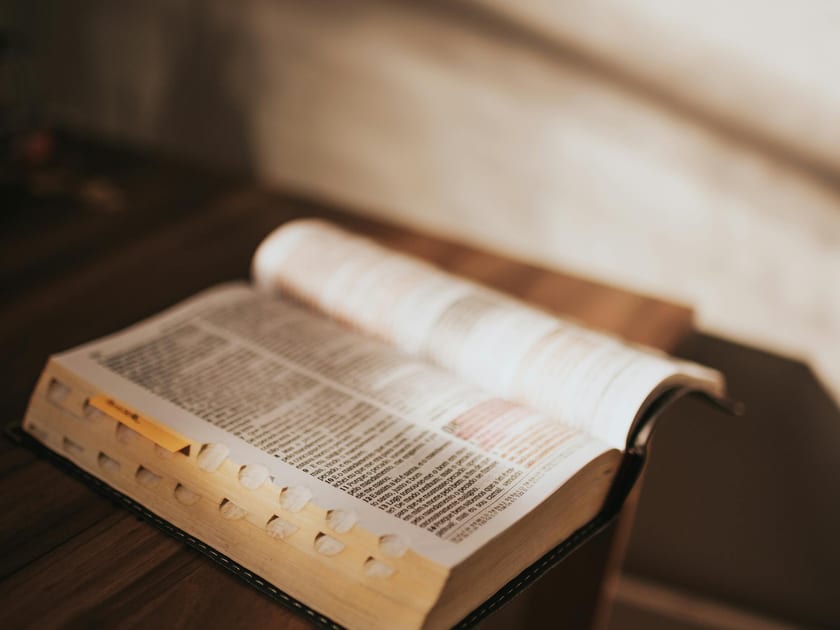 Open book resting on a wooden desk in soft sunlight